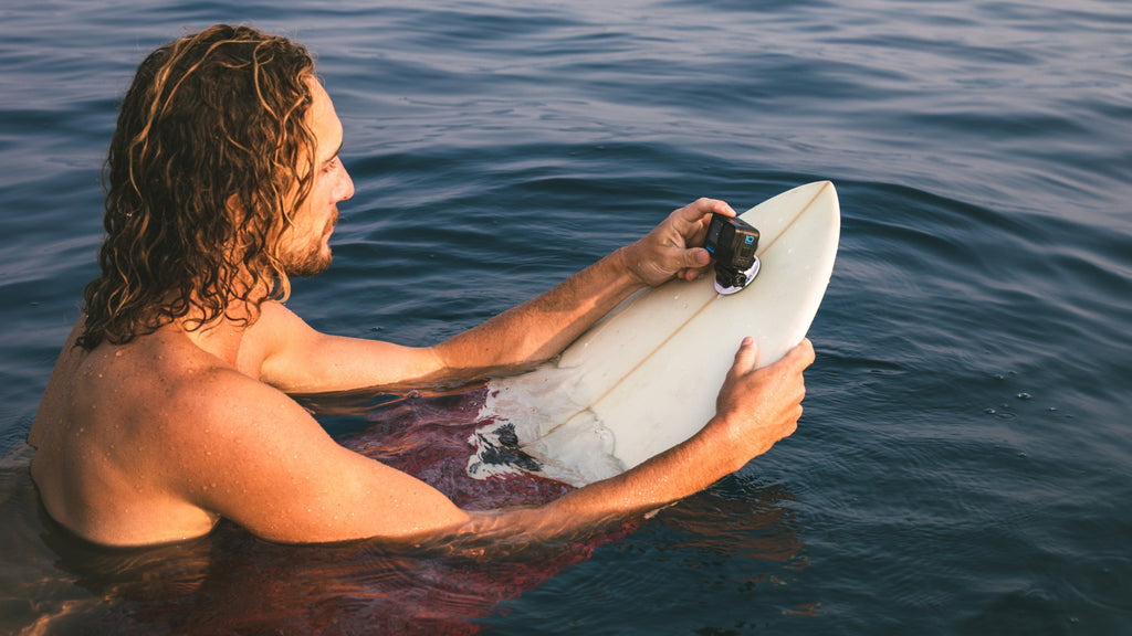 Surfer mounting GoPro to surfboard
